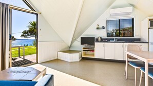 A compact kitchen with a dining area, a TV, and a view of the sea.