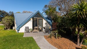 A house with a blue roof, a covered patio with outdoor furniture, and a well-maintained lawn.