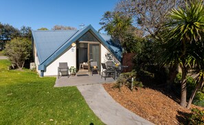 A house with a blue roof, a covered patio with outdoor furniture, and a well-maintained lawn.