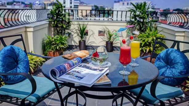 Terraza en la azotea con una mesa lista para el desayuno, incluyendo pan, un vaso de jugo y un periódico.