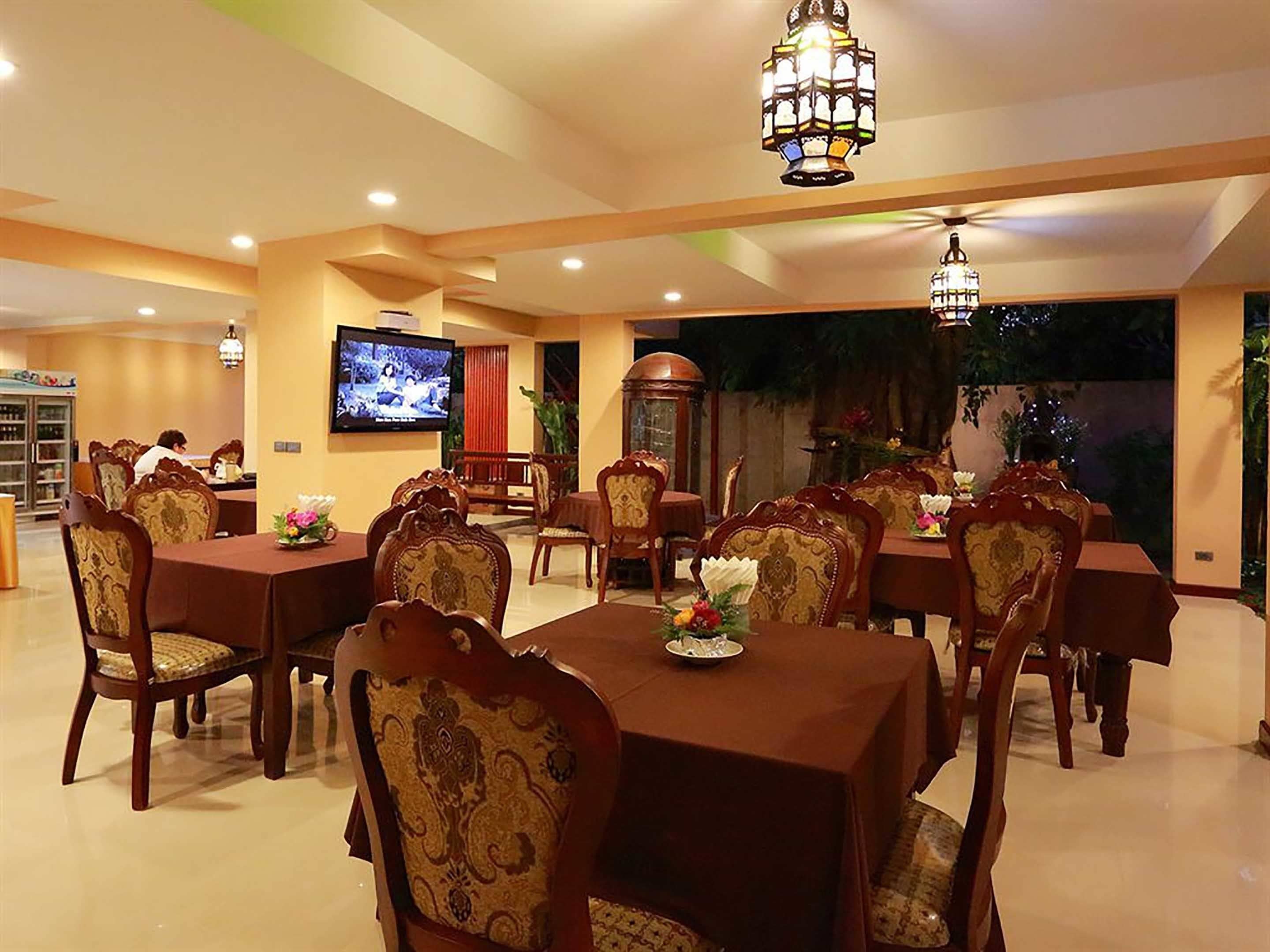 A dining area with multiple tables and chairs, a television mounted on the wall, and a view of the outdoors.
