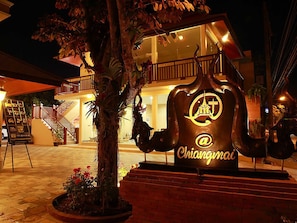 A building with a large sculpture of a musical instrument, a staircase, and a sign with the name "Chiangmai".