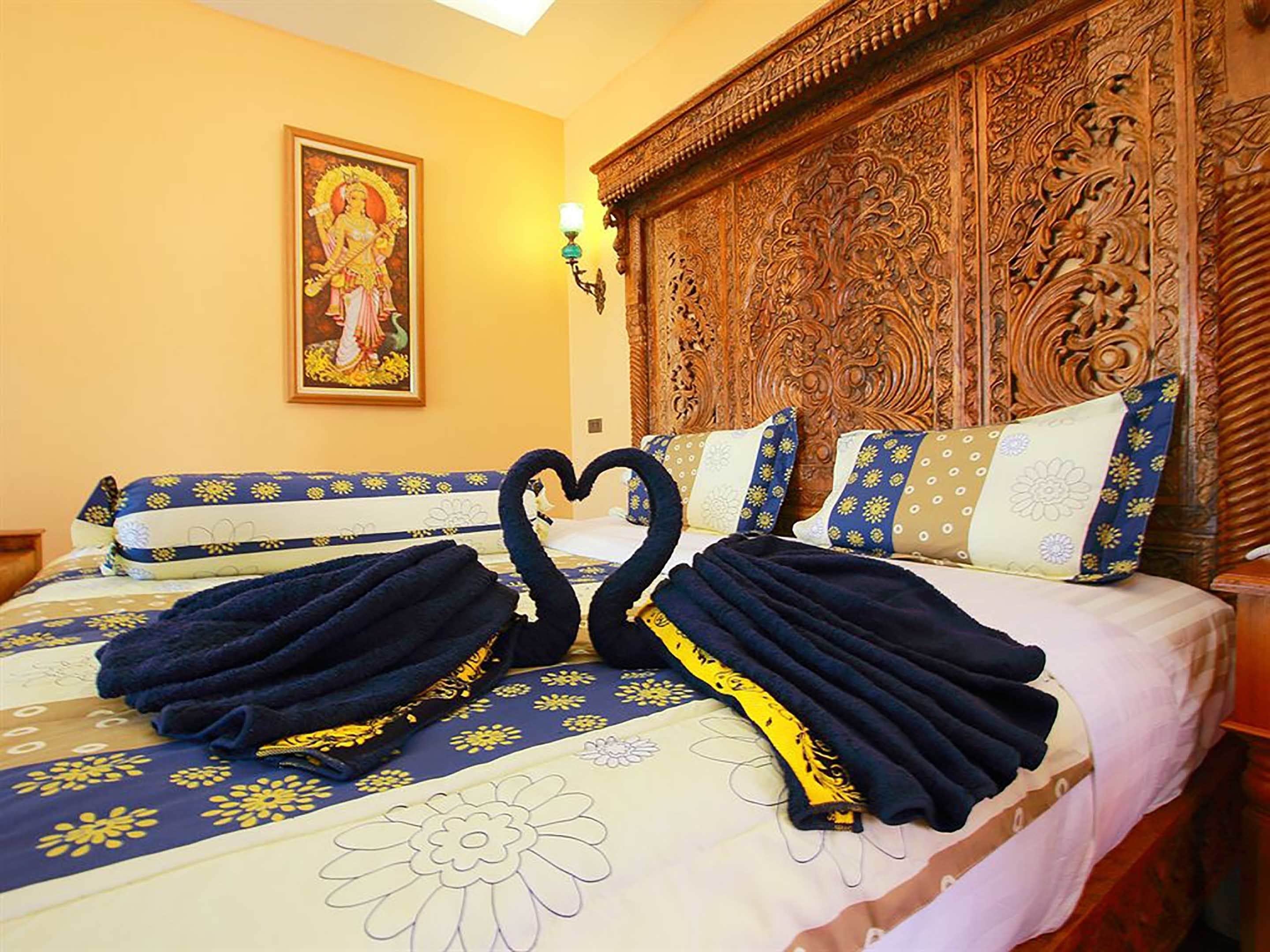 Una habitación de hotel con una cama grande, un cabecero de madera, una pintura mural y una mesita de noche.