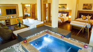 A hotel room with a large bed, a sitting area with a coffee table, a small pool, and a bathroom with a mirror and sink. - Aroma Beach Resort & Spa (Phu Thuy)