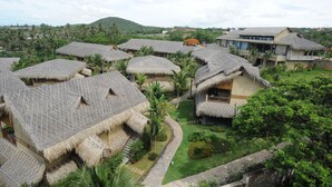 A resort with thatched-roof huts and a modern building with balconies. - Aroma Beach Resort & Spa (Phu Thuy)