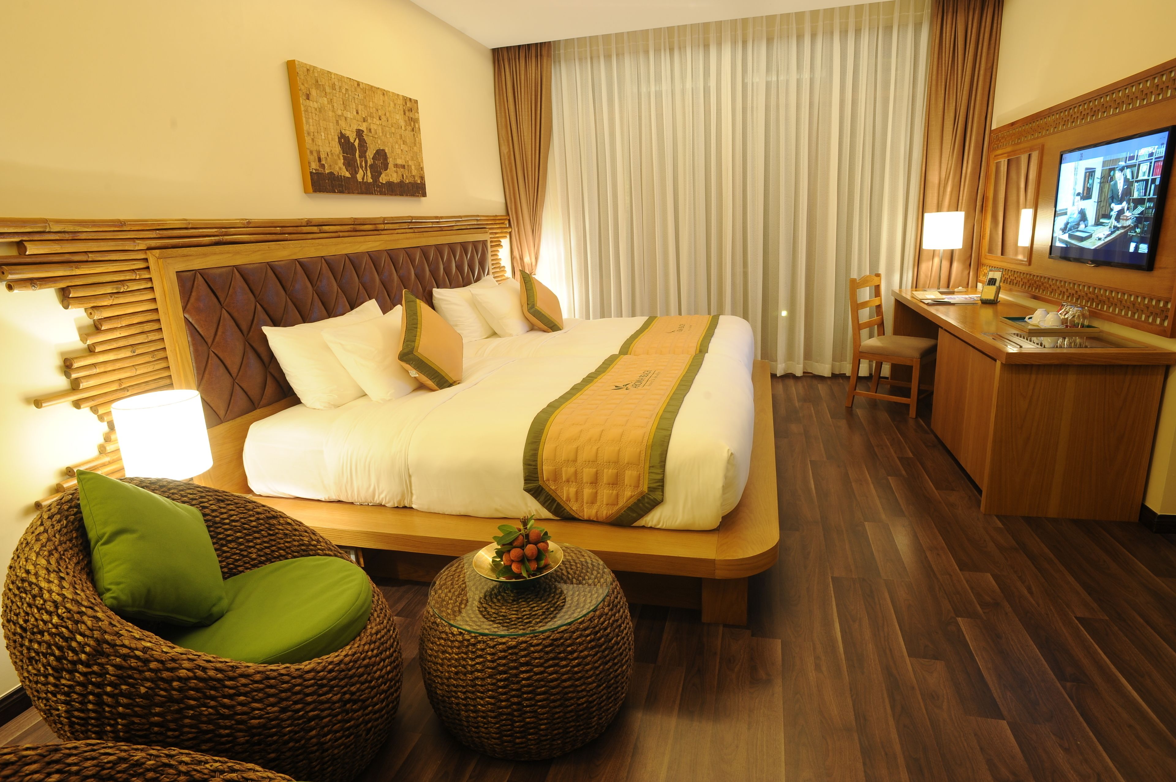 Ein Hotelzimmer mit einem großen Bett, einem Schreibtisch, einem Fernseher und einem Korbstuhl.