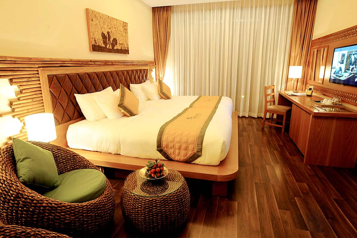 A hotel room with a large bed, a desk, a chair, and a television.