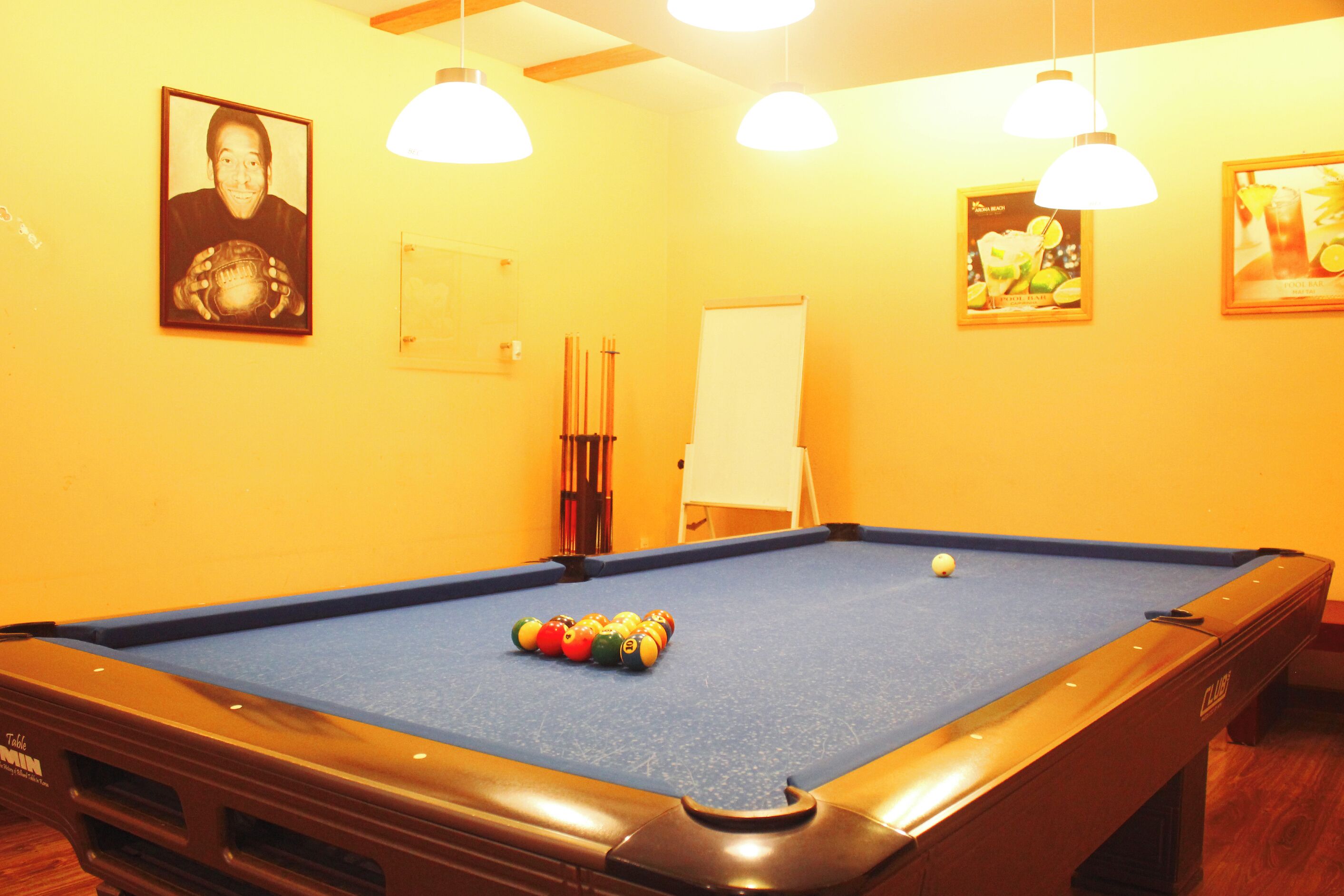 A pool table with balls, a whiteboard, and framed pictures on the wall.