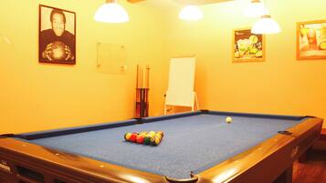 A pool table with balls, a whiteboard, and framed pictures on the wall.