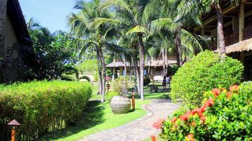 A tropical garden pathway leading to a building with thatched-roof structures.