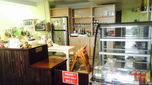 A restaurant interior with a counter, a refrigerator, shelves with jars, and a display case with beverages. - Dozy Lamoon House (Chiang Mai)