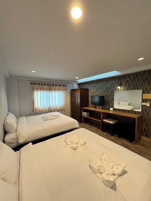 Habitación de hotel con dos camas, televisión, escritorio y un ventanal grande con cortinas.