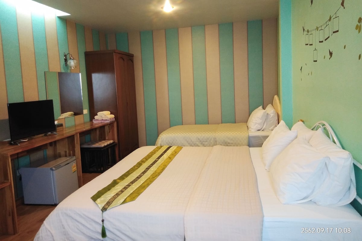 A hotel room with two beds, a desk with a television, and a wardrobe.