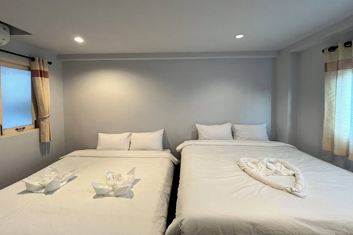 A hotel room with two beds, each with white linens and pillows, and a decorative towel arrangement on the beds.