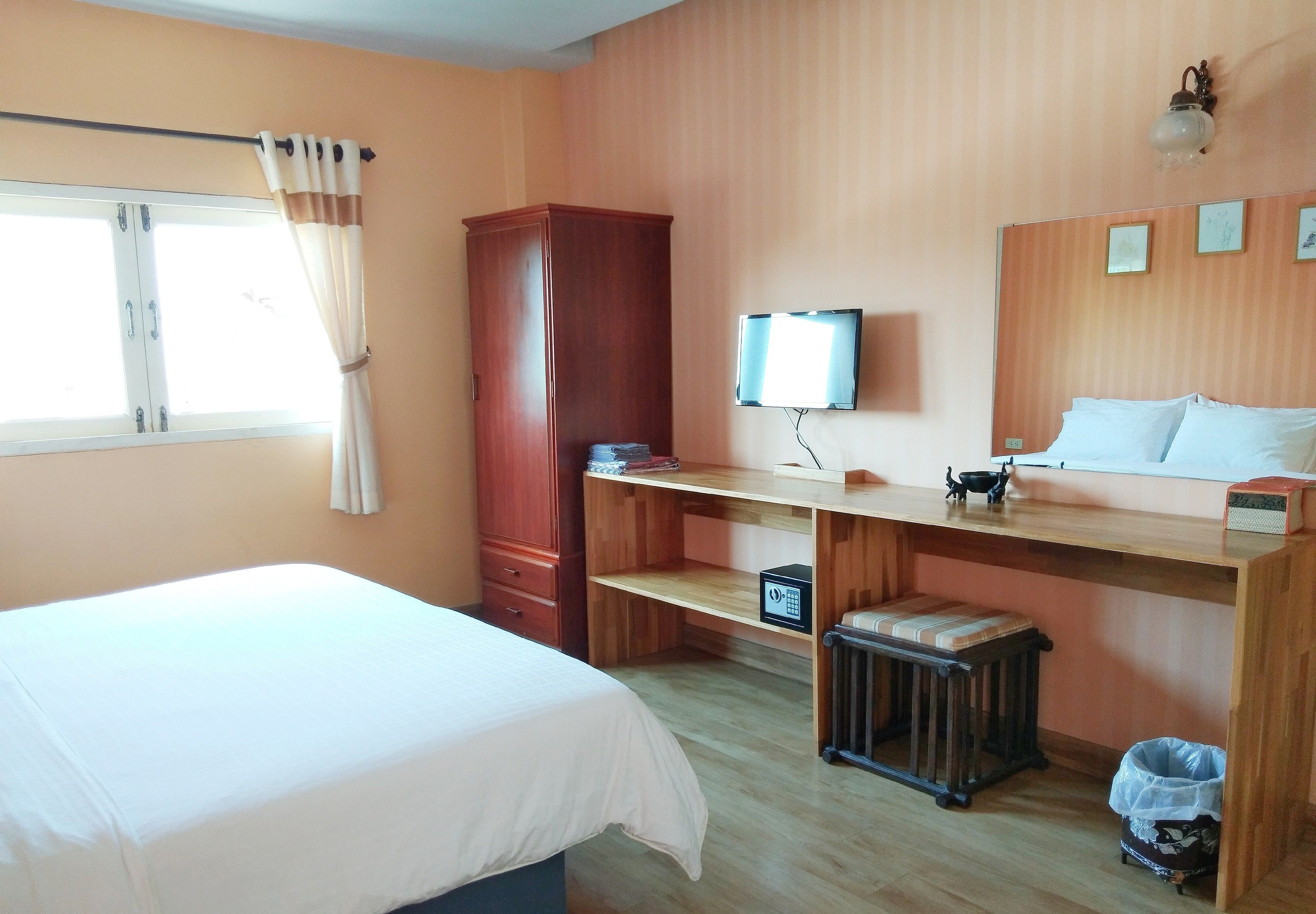 Una habitación de hotel con cama, un escritorio de madera, televisión, armario y radiador.