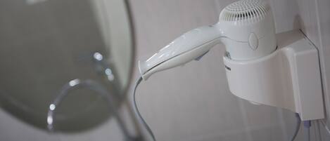 A hair dryer mounted on a wall in a bathroom.