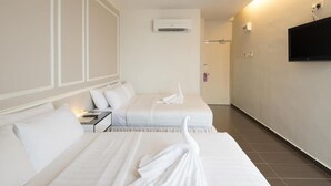 Habitación de hotel con dos camas, un televisor montado en la pared y un equipo de aire acondicionado.