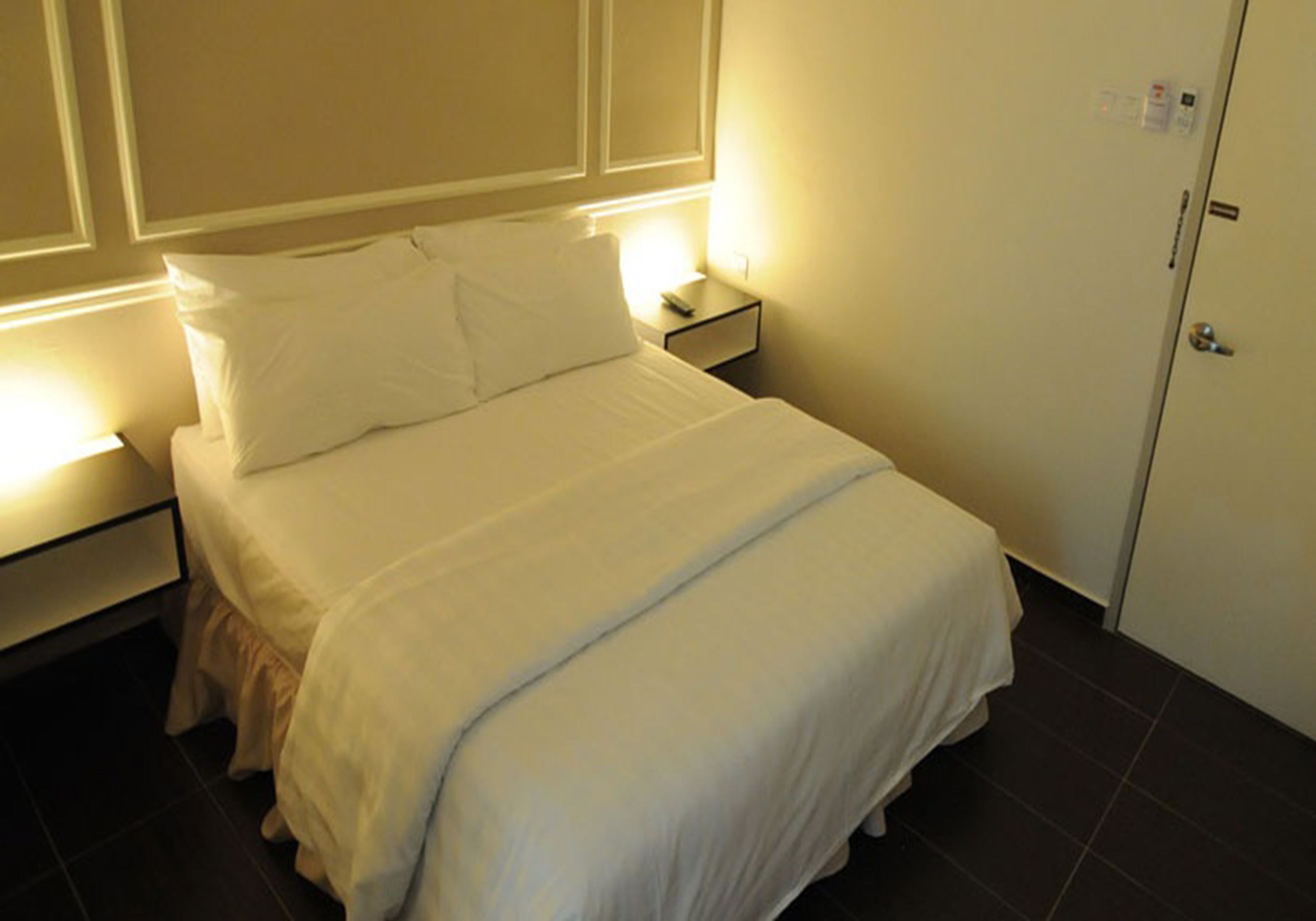 A neatly made bed with white bedding in a hotel room.