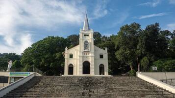 A church with a tall steeple, surrounded by trees and a staircase leading up to it.
