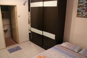 A bedroom with a bed, a wardrobe, and a bathroom visible through an open door.