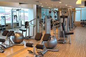 A gym with various exercise equipment, large windows, and a wooden floor. - Galaxy Hotel Banjarmasin (Banjarmasin)