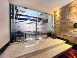A modern interior with a glass wall labeled 'SMOKING AREA,' a marble staircase, and a wooden wall panel. - Galaxy Hotel Banjarmasin (Banjarmasin)