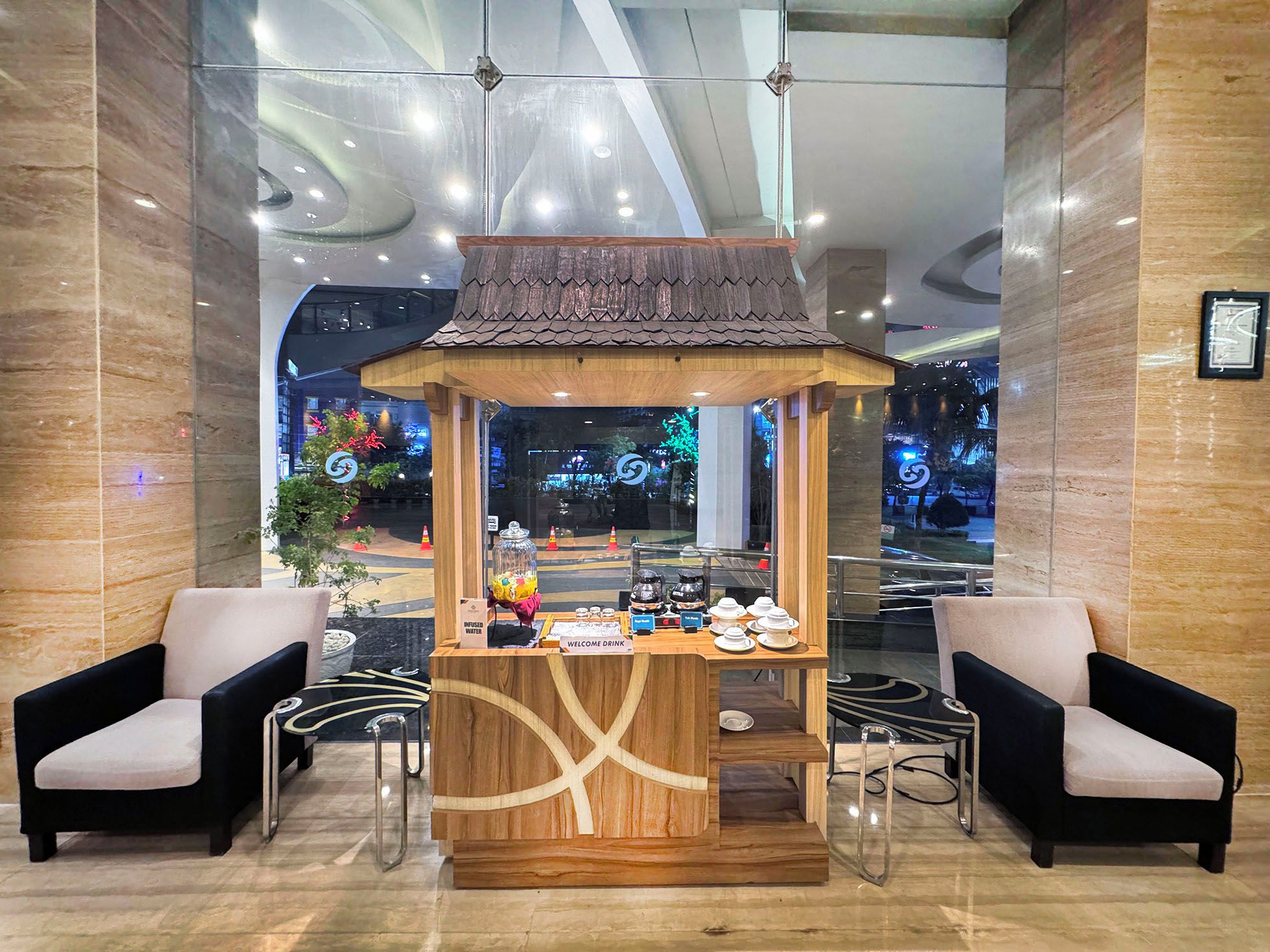 A reception area with a wooden kiosk, two armchairs, and a glass partition.