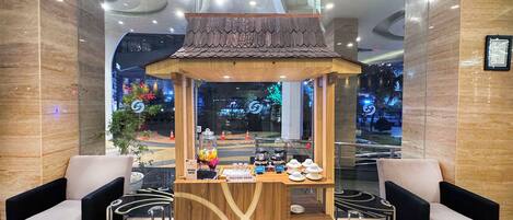 A reception area with a wooden kiosk, two armchairs, and a glass partition.