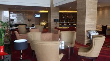 A hotel lobby with multiple seating areas, a bar, and a television screen.