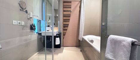 A modern bathroom with a glass shower enclosure, a toilet, a sink with a mirror, and a bathtub with a towel.