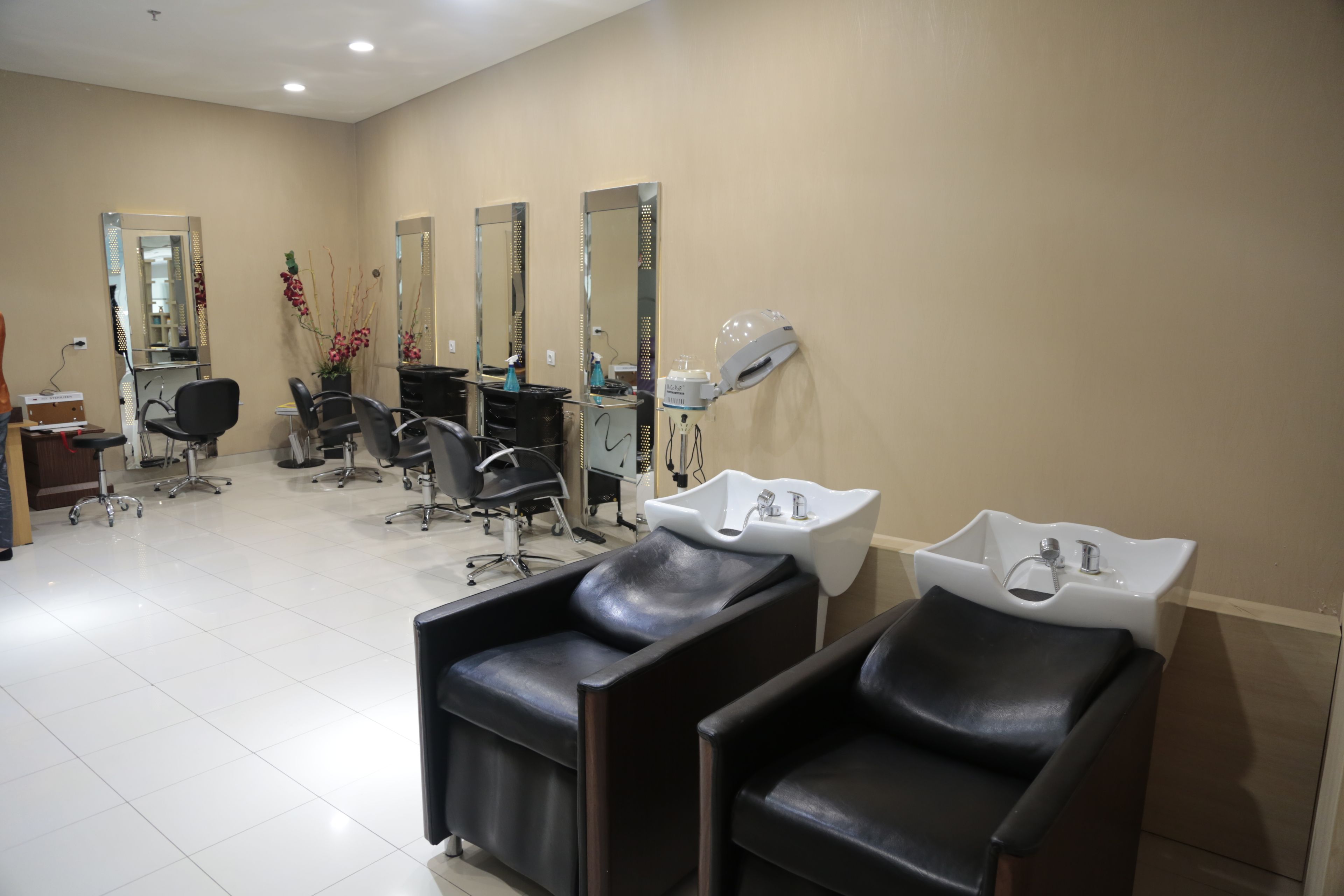 Un salon équipé de plusieurs fauteuils, de miroirs et de lavabos.
