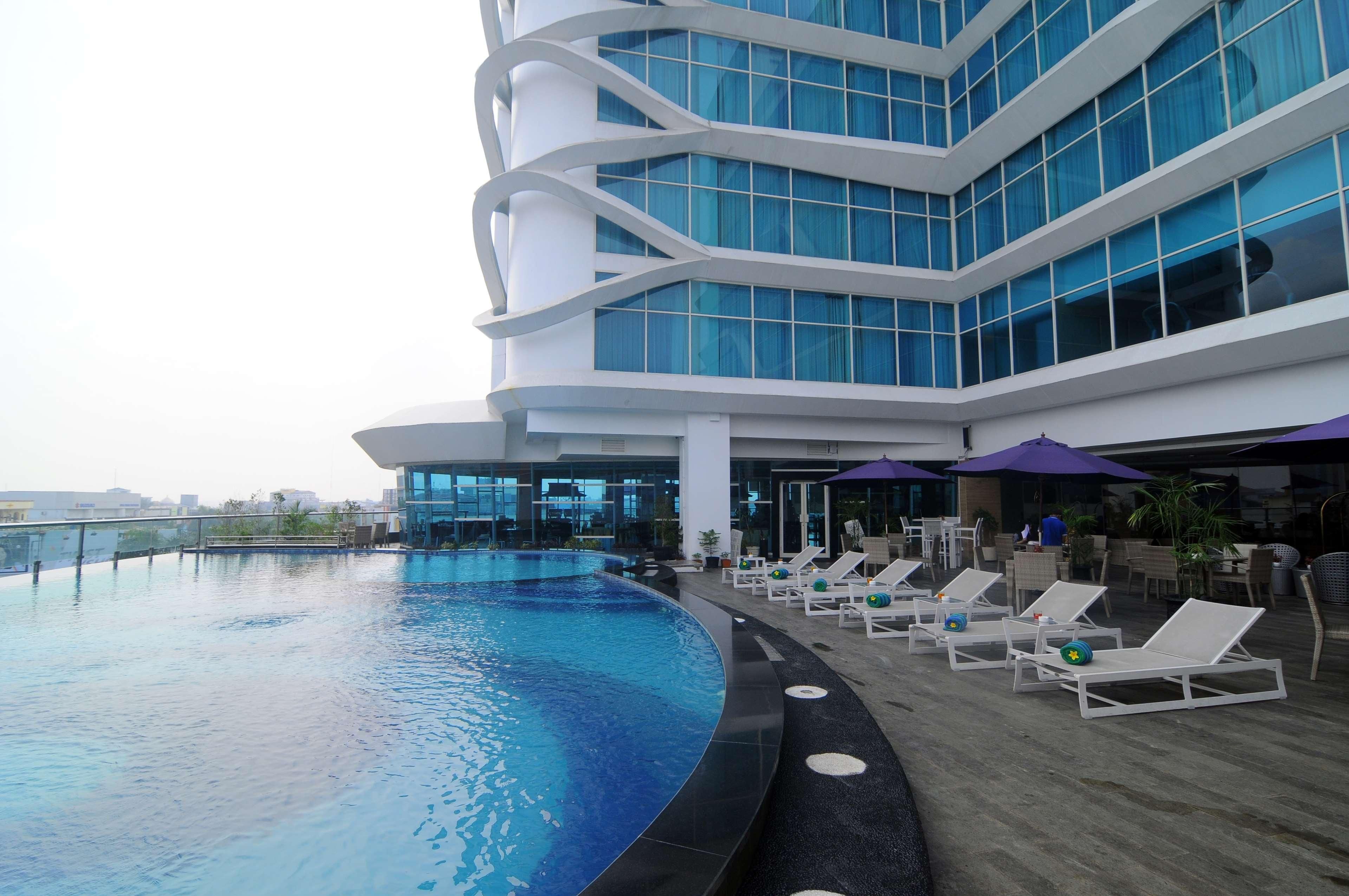 A modern building with a swimming pool and lounge chairs.