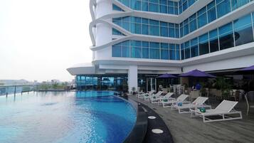 A modern building with a swimming pool and lounge chairs.