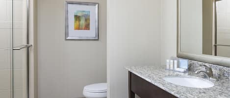 A modern bathroom with a marble sink, a large mirror, and a framed artwork on the wall.