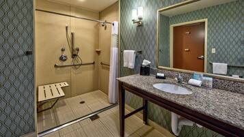 A bathroom with a walk-in shower, a sink, and a mirror.
