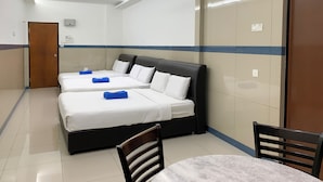 Une chambre d’hôtel avec deux lits, un ventilateur de plafond, une table et des chaises.