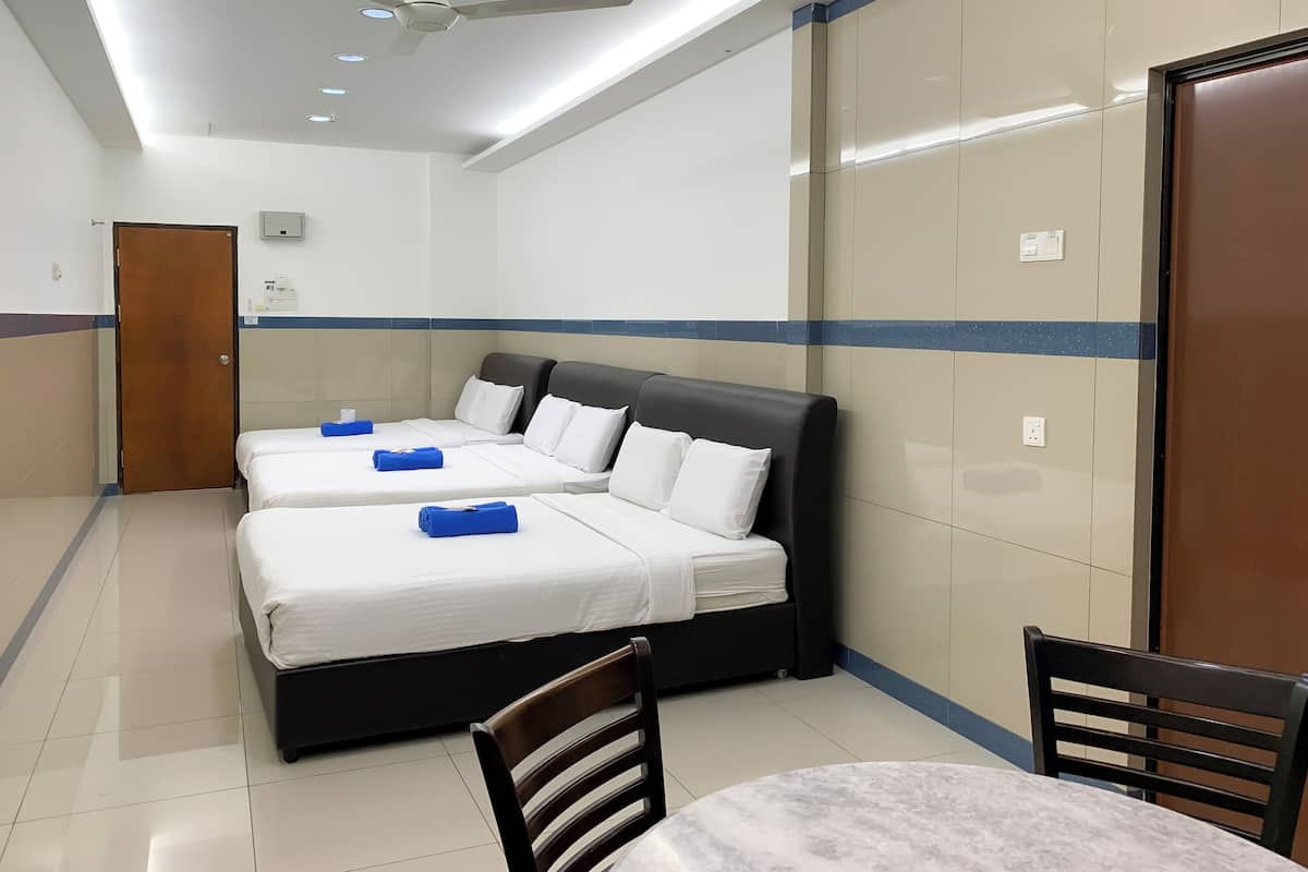 A hotel room with two beds, a ceiling fan, a table, and chairs.