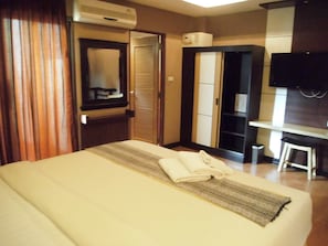 Une chambre d’hôtel comprenant un lit, un bureau, une chaise, une armoire et un téléviseur.