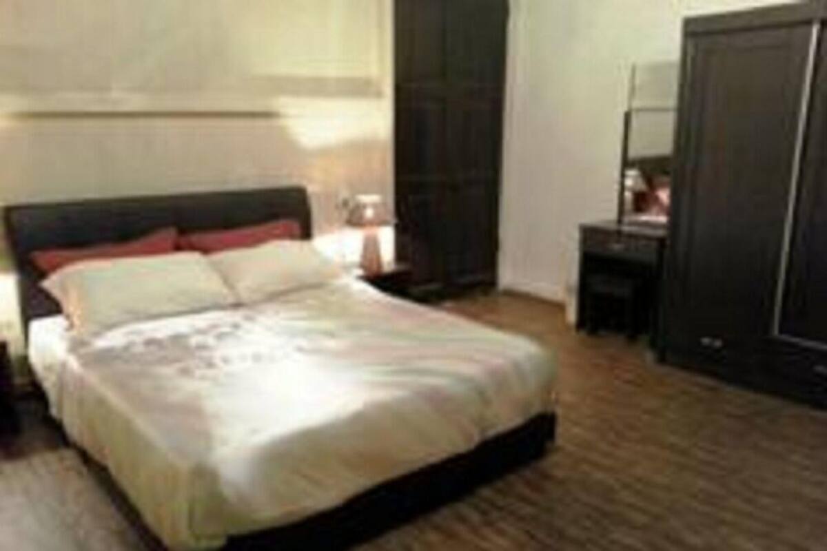 A bedroom with a bed, a nightstand, a dresser, and a wardrobe.