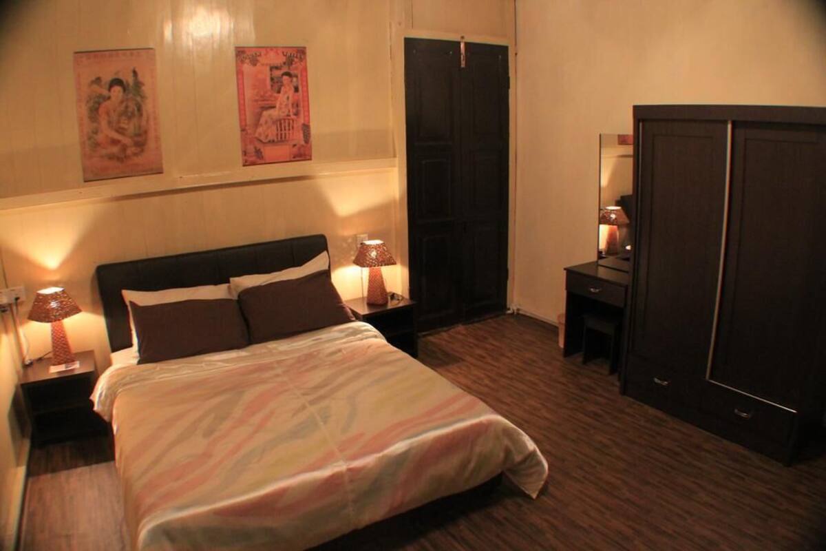 A bedroom with a bed, nightstands, a desk, and a wardrobe.
