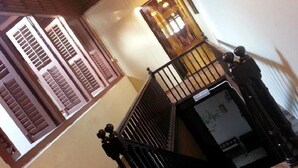 A staircase with a black railing and a small landing area with a white wall and a window. - Muntri House - Hostel (George Town)