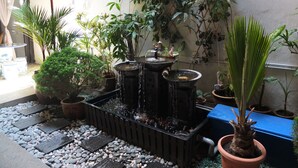 A courtyard with a water feature, potted plants, and a tiled floor. - Muntri House - Hostel (George Town)