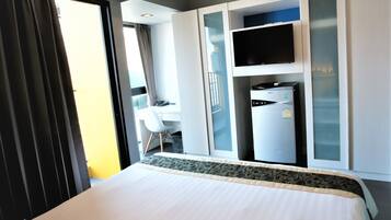 Una habitación de hotel con cama, escritorio, televisor y minibar.