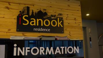 A sign for 'iSanook Residence' with a silhouette of a cityscape and a 'RESIDENCE' label. Below, a counter with 'INFORMATION' written on it.