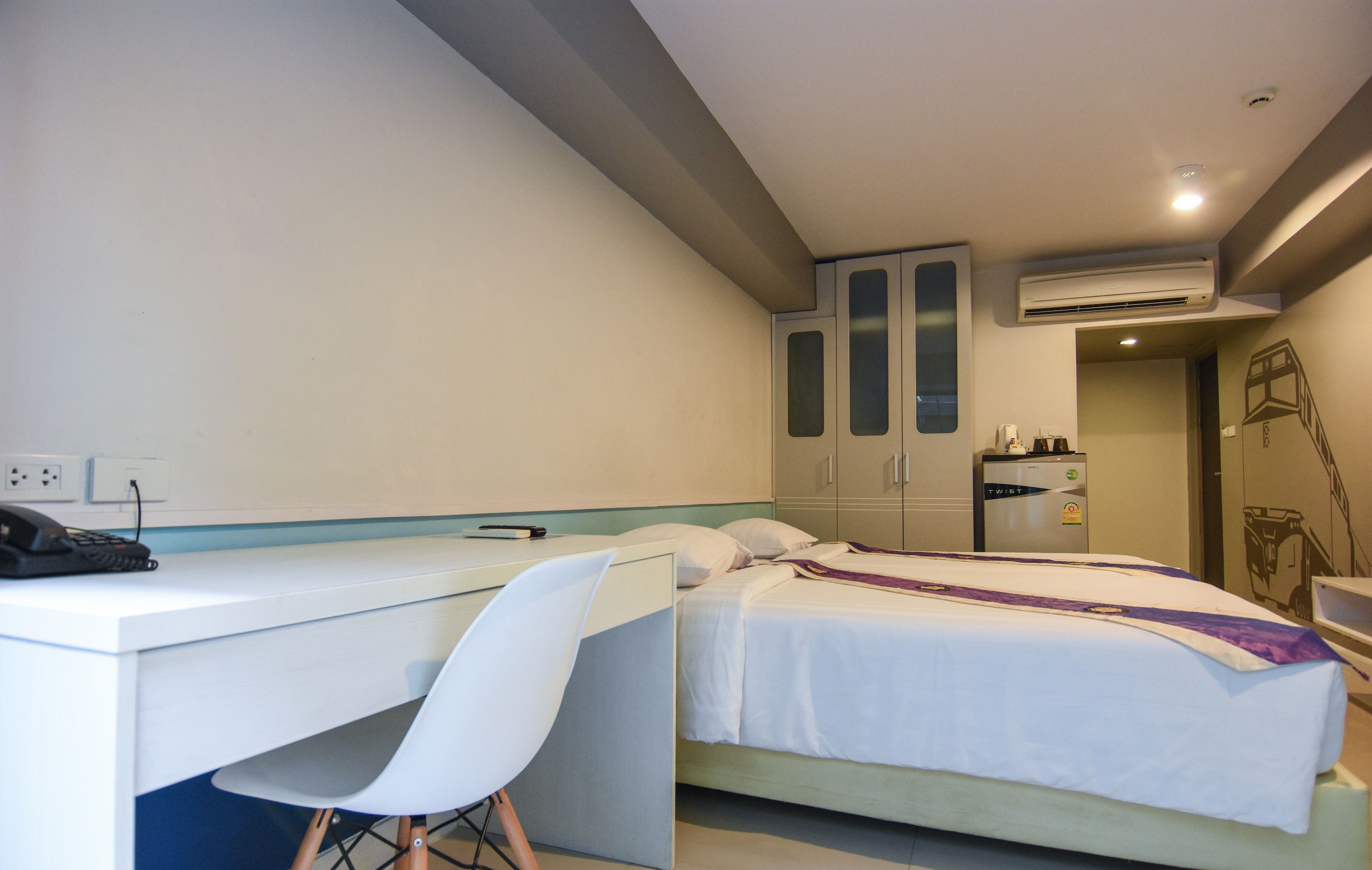 A bedroom with a bed, a desk, a chair, and a wardrobe.