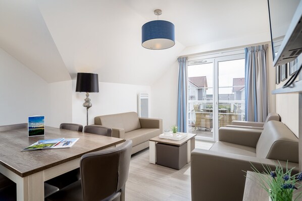 Una sala de estar moderna con una mesa de comedor, sofá y un ventanal con cortinas.