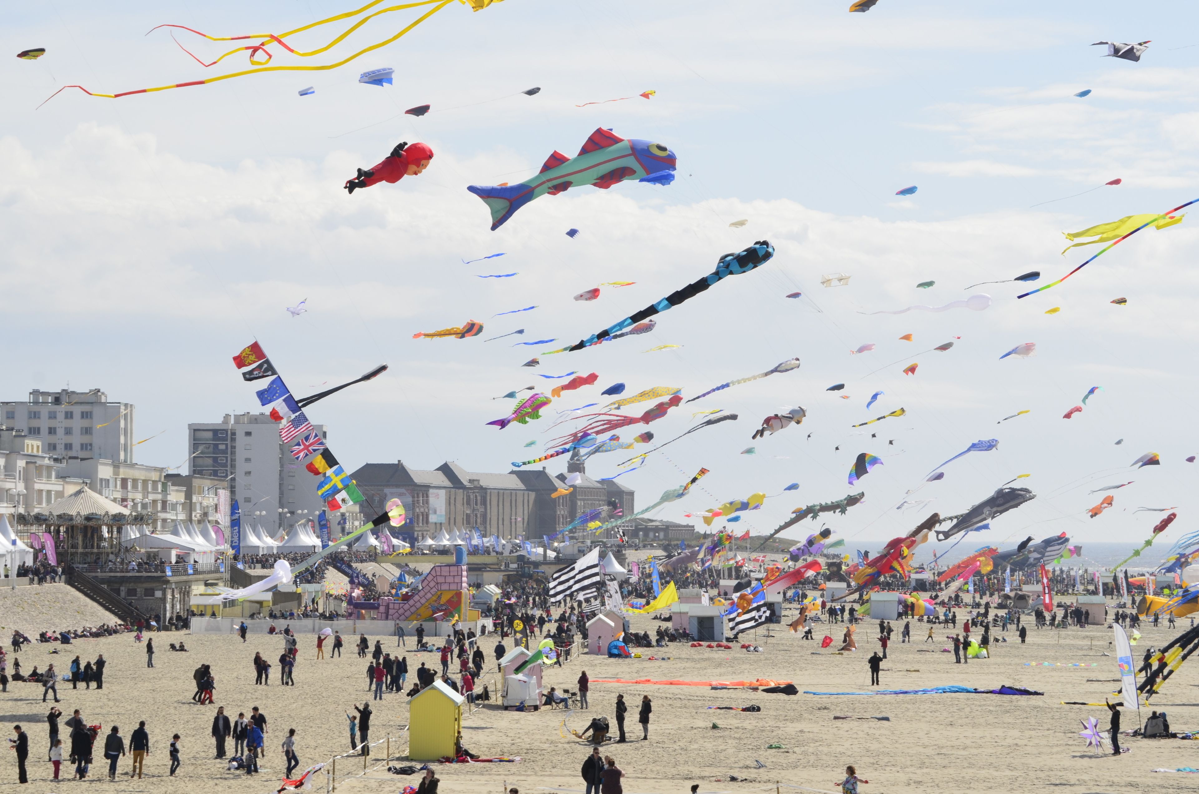 A beach with numerous kites flying in the sky.