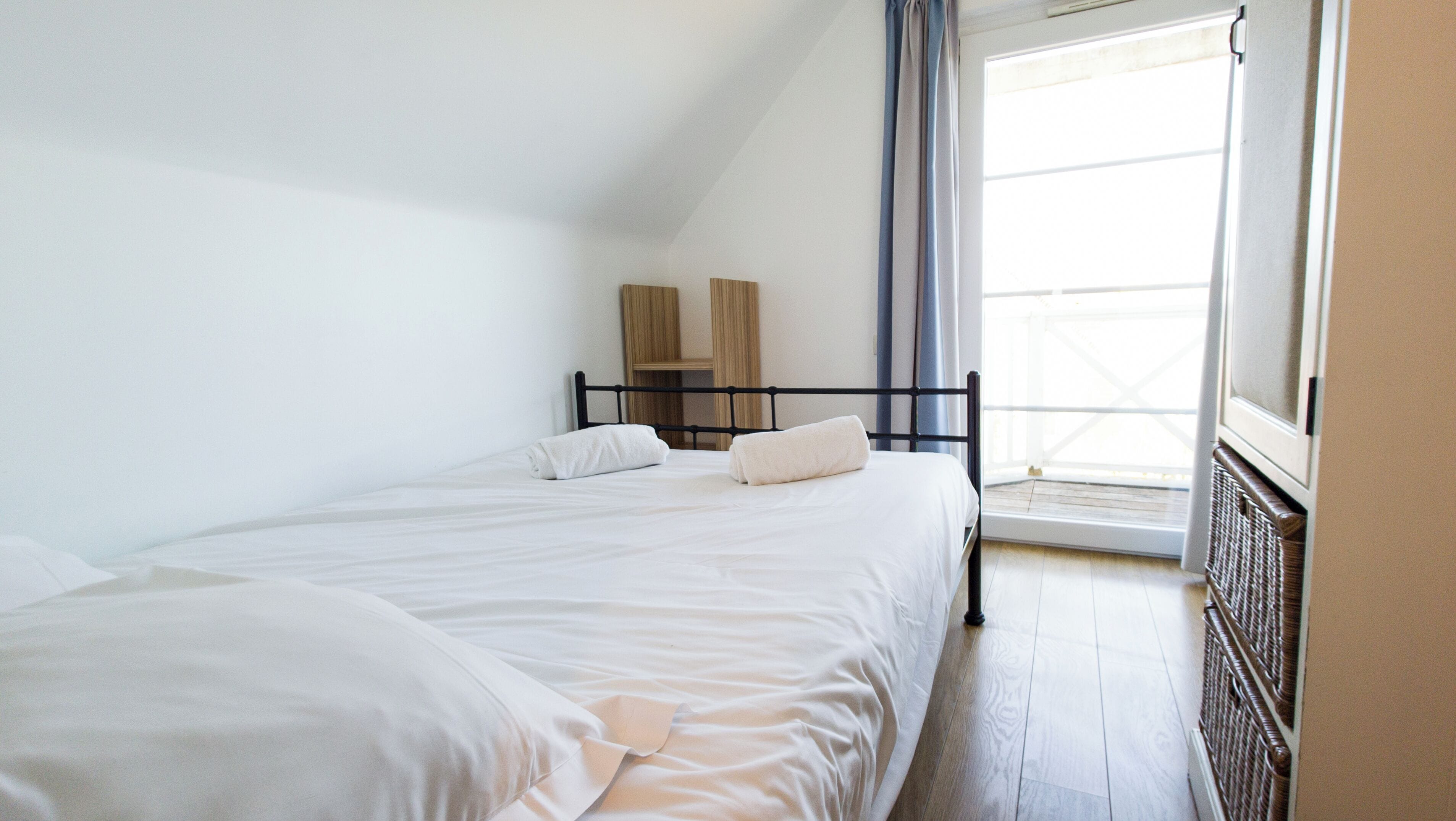 Una camera da letto con due letti, una finestra con tende e un termosifone.