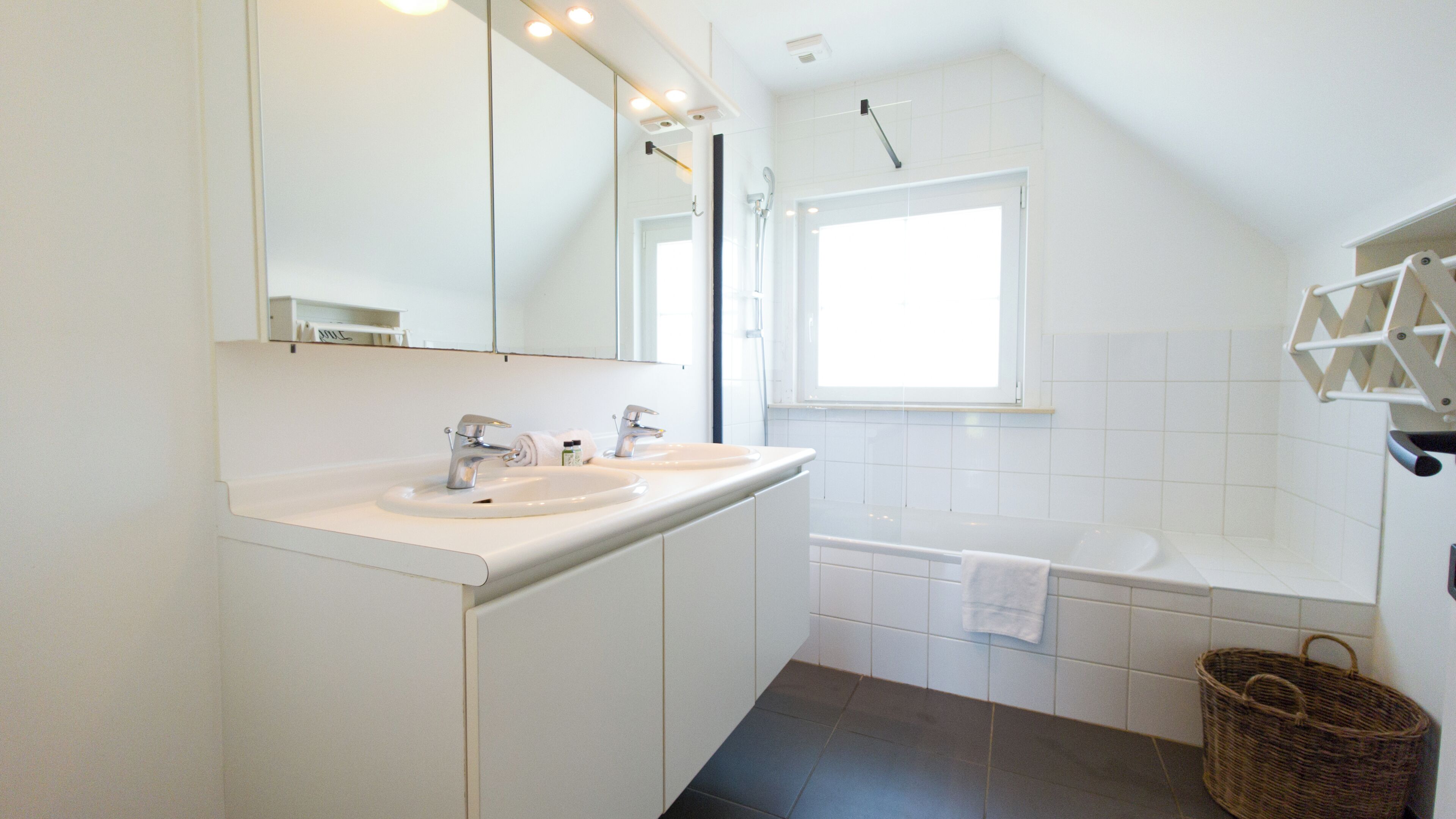 A modern bathroom with two sinks, a mirror, a shower, and a window.