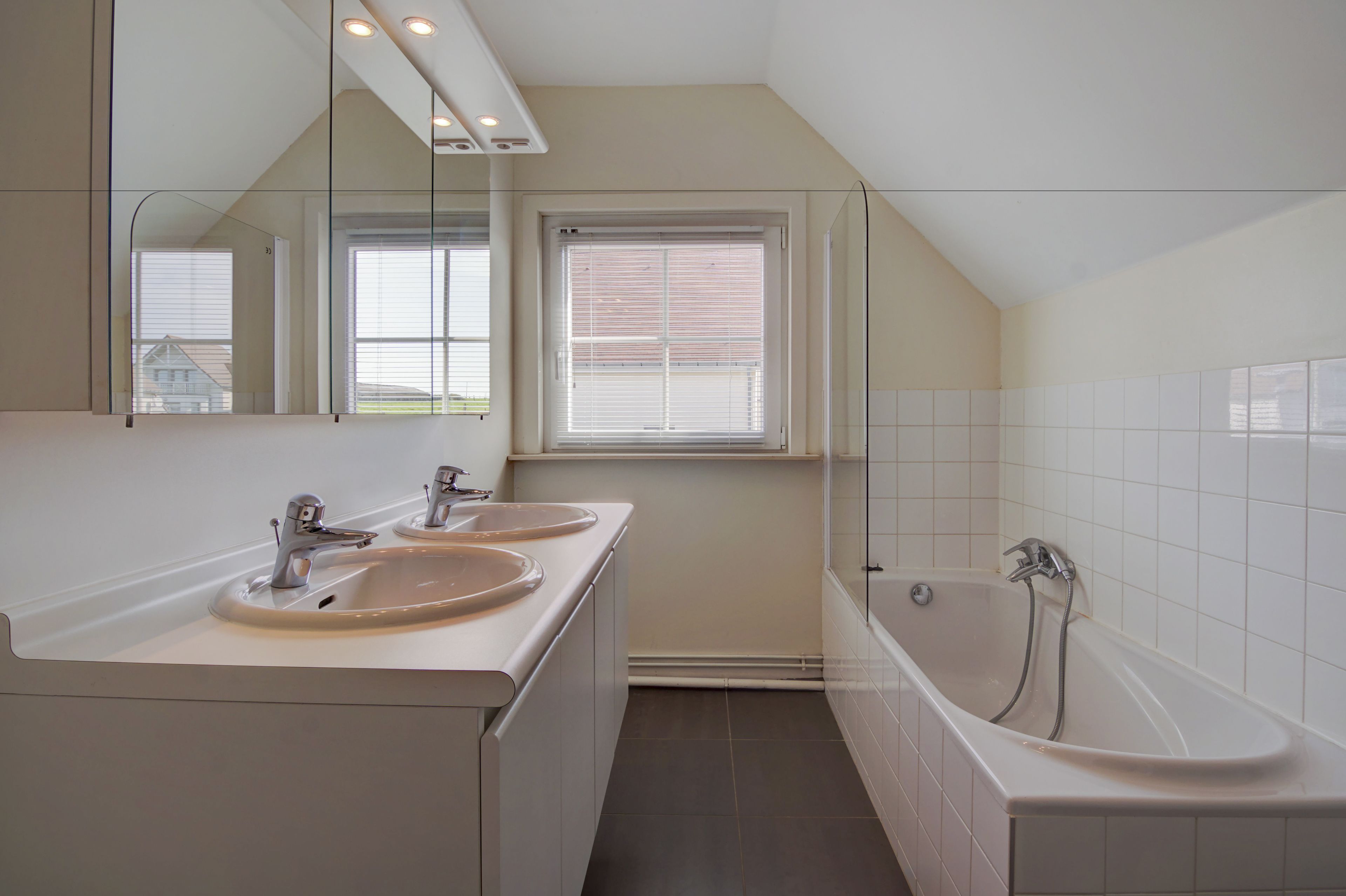 Un baño moderno con lavamanos doble, bañera y un espejo grande.